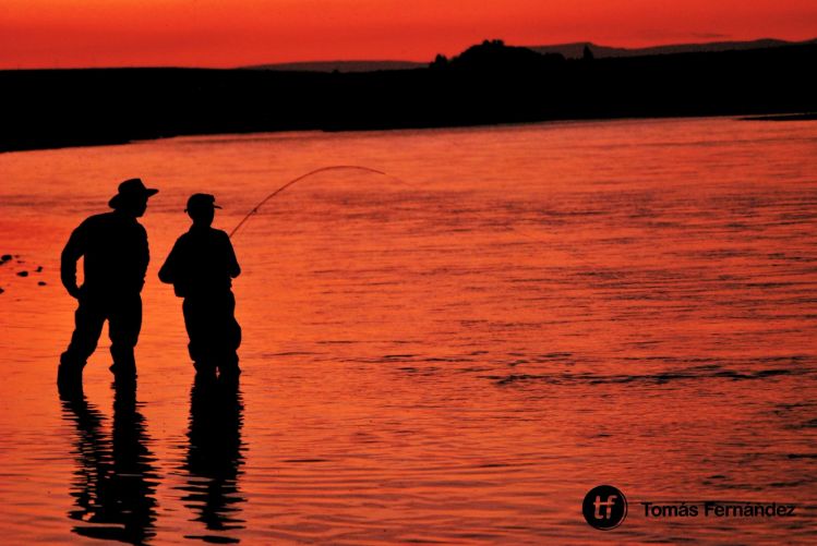 Facundo enseñándole a pescar a Nicanor (padre e hijo) en un mágico atardecer.